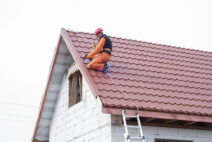 47751738 - builder performs installation gable roof tiles of metal