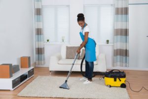 48645395 - young african woman cleaning carpet with vacuum cleaner