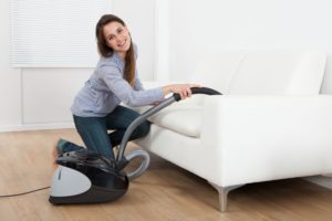 30338981 - full length side view of young woman vacuuming sofa at home